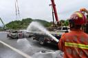 A firefighter sprays water on the remains of a car in the aftermath of the collapse (Xinhua via AP)
