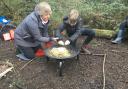 Sian lighting a fire in the schools outdoor area with one of the year 6 children