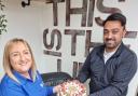 Diane Hughes, of Furniture for Life, with the massage chair, being handed a cake by Deaf Village staff member Habib Hussain