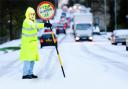 WHITE BLANKET A lollipop man stops traffic on a snowy Hibson Road, Nelson