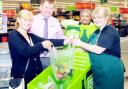 Dee Adams (left) hands over a bag of food to foodbank volunteer Heather White watched by Asda manager Paul Wilcox and Community Life champion Barratt Palmer