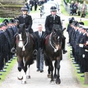 SOMBRE: Police colleagues stand to attention as the funeral cortege passes