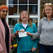 Banu Adam, Arts 2 Heal manager (left) and  Ann Shuttleworth, Arts 2 Heal volunteer, (centre) receiving a cheque from Yvonne Brown, volunteer at The Dog Inn (right) in memory of Tracey Haslam.