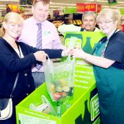 Dee Adams (left) hands over a bag of food to foodbank volunteer Heather White watched by Asda manager Paul Wilcox and Community Life champion Barratt Palmer