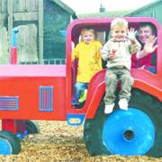 PLAY DAY: Tractor creator Heath Kershaw tries out the fun attraction for himself with the help of three-year-olds Sam Farnworth and Amber Carter
