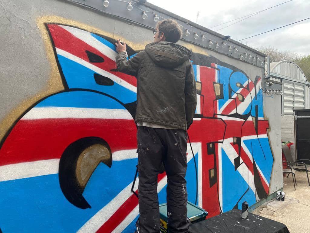 Keiron Curly Whitehead, Darwens resident grafitti artist has painted a huge Union Jack on the side of the British Queens beer garden ready for the pubs re-opening on May 17
