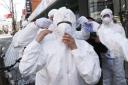 A worker wears a face mask to spray disinfectant as a precaution against the coronavirus at a shopping street in Seoul, South Korea, Thursday, Feb. 27, 2020. South Korea and China each reported hundreds more virus cases Thursday as the new illness persist