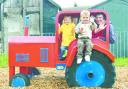 PLAY DAY: Tractor creator Heath Kershaw tries out the fun attraction for himself with the help of three-year-olds Sam Farnworth and Amber Carter