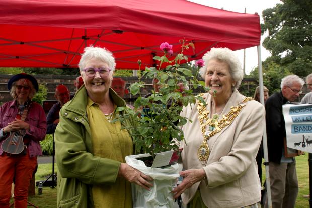 Mayor Councillor Anne Cheetham presents Chair of Bacup Pride Pat Smith with a red rose in memory of Sylvia Lancaster.