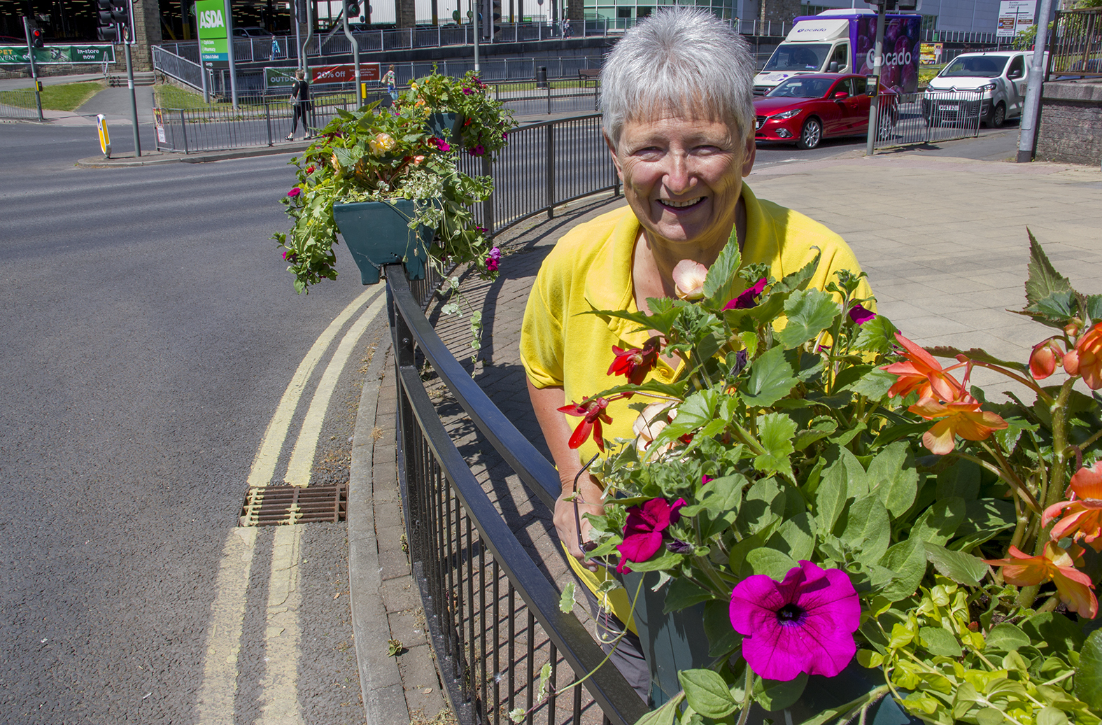 Sue Shuttleworth, Chair of Civic Pride, with one of many railing baskets that are already brightening up Rawtenstall