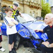 SERIOUS MESSAGE: Jake and Michael Glover are shown a crashed vehicle at the roadshow by fire station manager Ian Potter and PC Mark Royle Evatt