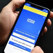 A person holding a mobile phone displaying the NHS app (Kirsty O’Connor/PA)
