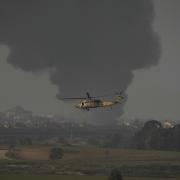 An Israeli military helicopter flies near the Israeli-Gaza border, as seen from southern Israel, Monday, Jan. 1, 2024. The army is battling Palestinian militants across Gaza in the war ignited by Hamas' Oct. 7 attack into Israel. (AP Photo/Leo