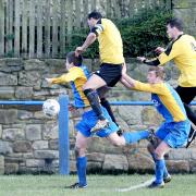 SYNCHRONISED: Barnoldswick Town players, in blue and yellow, challenge for the ball