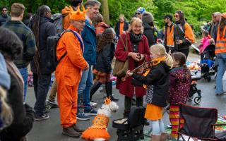 An orange-clad man and his orange-clad dog listen to a girl playing violin during King’s Day celebrations in Amsterdam on Saturday (Peter Dejong/AP)